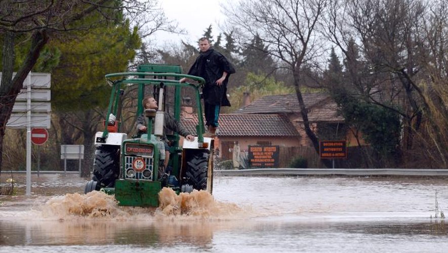 Un homme utilise un tracteur le 19 janvier 2014 pour circuler sur une route inondée à Hyères