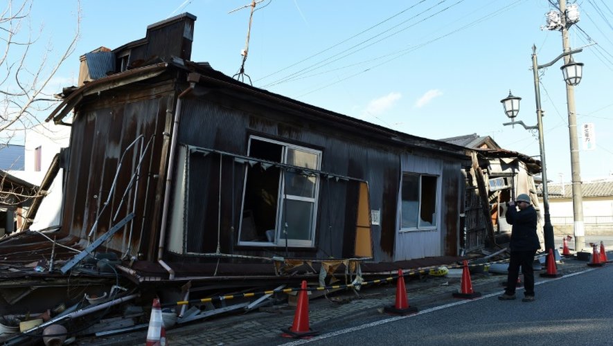Un "touriste" photographie une des maisons abandonnées de Namie, dans la région de Fukushima, le 11 février 2016, 5 ans après l'accident nucléaire