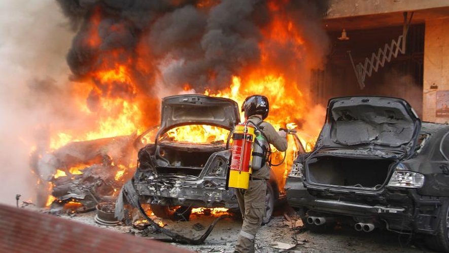 Un pompier libanais tente d'éteindre deux véhicules en flamme, après une explosion, le 21 janvier 2014 à Beyrouth