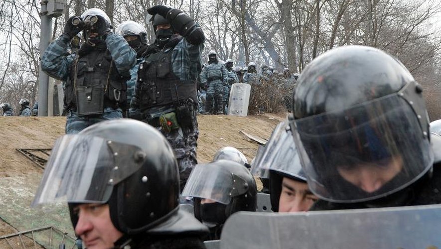 Des policiers surveillent les manifestants à l'aide de jumelles à Kiev, le 21 janvier 2014