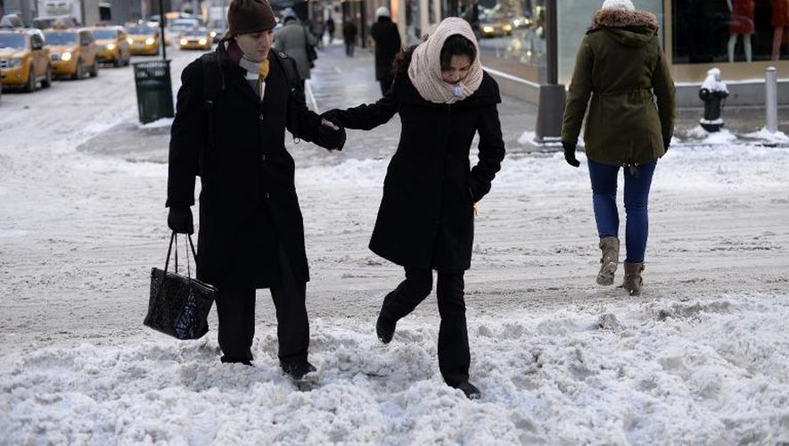 Un homme et une femme traversent une rue enneigée à New York le 22 janvier 2014