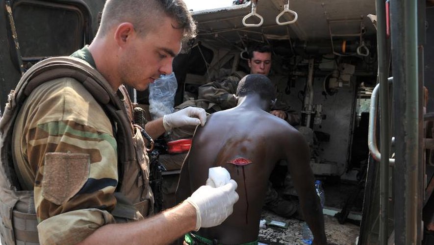 Des soldats français de la force Sangaris soignent un homme attaqué à coup de machettes dans le quartier PK 12, mercredi 22 janvier 2014