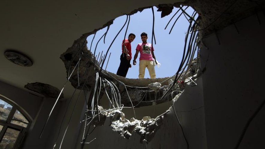 Des Yéménites regardent à travers le toit d'une maison éventrée la veille par une frappe aérienne de la coalition arabe, le 21 avril 2015 à Sanaa, près de la base de missiles de Fajj Attan