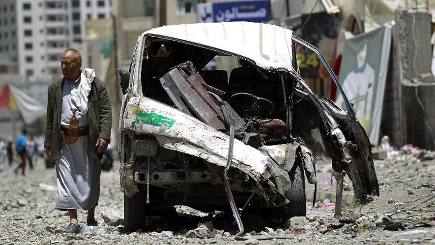 Un homme passe devant un véhicule détruit par des frappes aériennes de la coalition arabe à Sanaa (Yémen) le 21 avril 2015