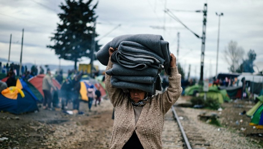 Une femme transporte des couvertures dans un camp provisoire à la frontière gréco-macédonienne près du village grec d'Idomeni, le 9 mars 2016