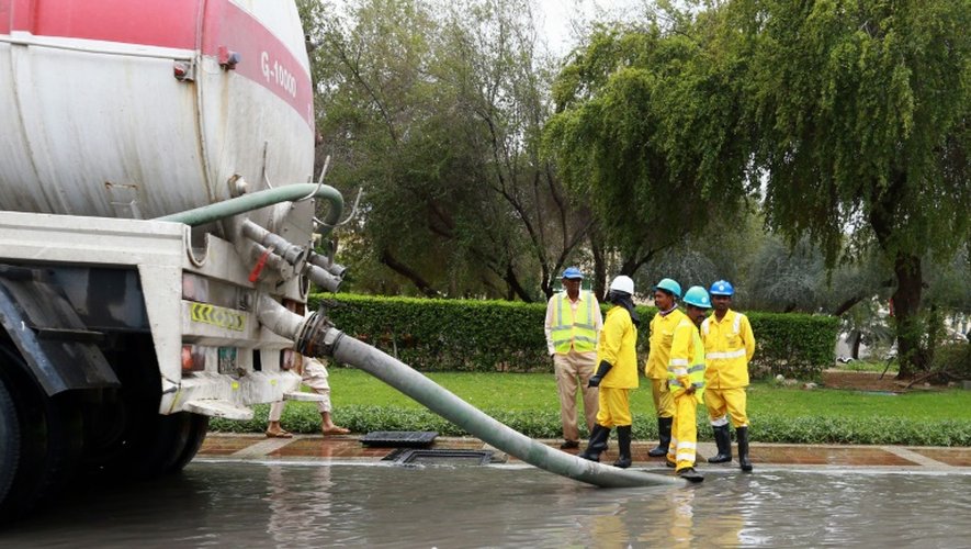 Des employés municipaux pompent de l'eau d'une rue après après des intempéries à Abou Dhabi, le 9 mars 2016