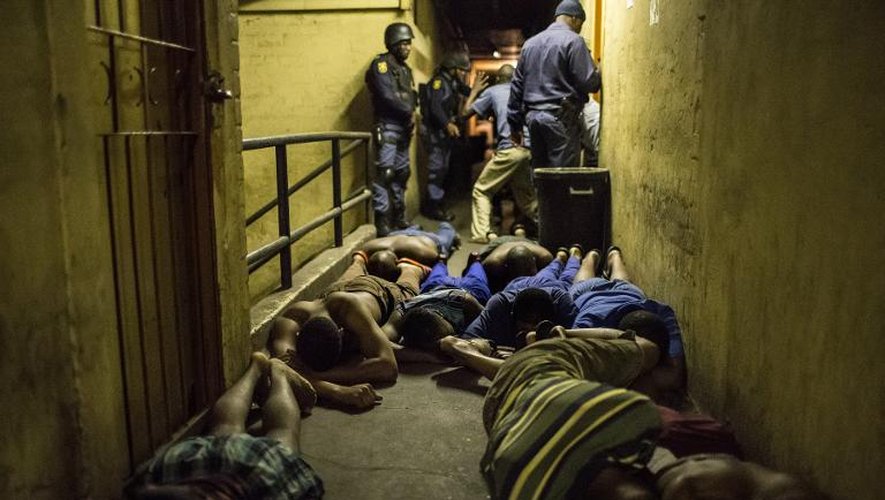 Des Sud-africains allongés face contre terre lors d'un raid nocturne de la police sud-africaine épaulée par l'armée le 21 avril 2015 un foyer hébergeant des travailleurs à Jeppestown