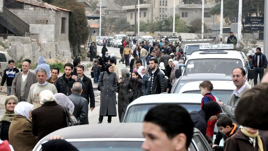 Photo fournie le 25 janvier 2014 par l'agence de presse syrienne SANA montrant des familles fuyant leur domicile de Barzeh banlieue de Damas
