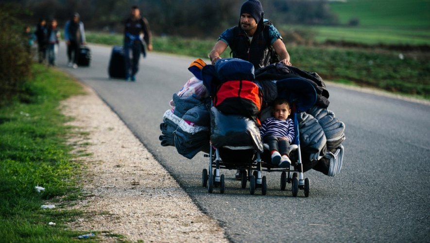 Un homme transporte dans une poussette son fils et des affaires personnelles sur une route près de la frontière entre la Grèce et la Macédoine, le 8 mars 2016
