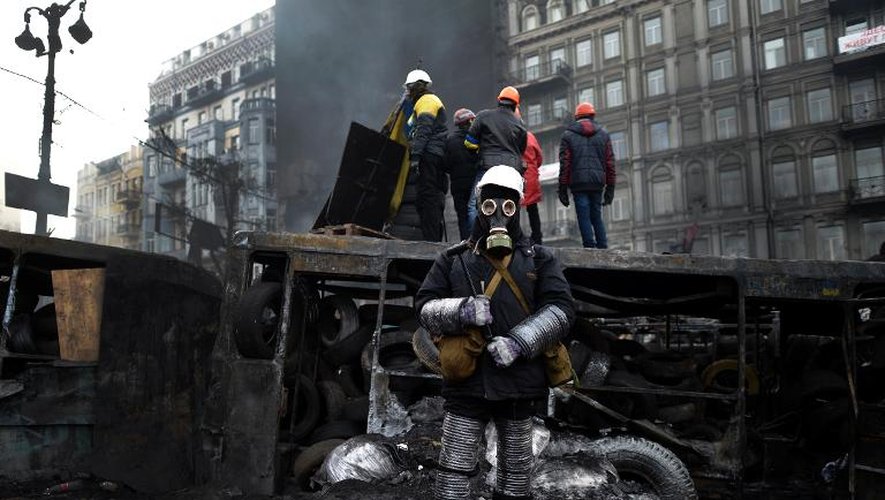 Un opposant, portant casque et masque à gaz, devant une barricade à Kiev, le 26 janvier 2014