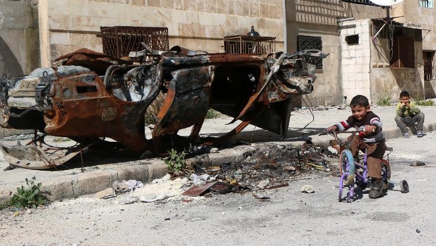 Un jeune garçon passe devant une carcasse de voiture le 25 avril 2015 à Alep