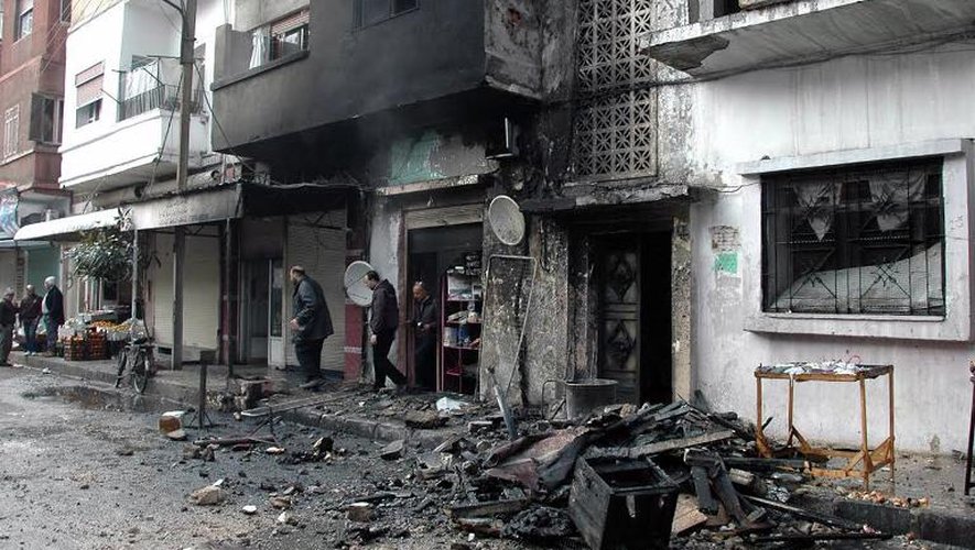 Des habitants dans une rue de Homs après des tirs au mortier de rebelles syriens, le 9 janvier 2014