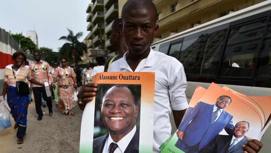 Un homme pose avec des affiches montrant le président Alassane Ouattara à Abidjan, le 25 avril 2015