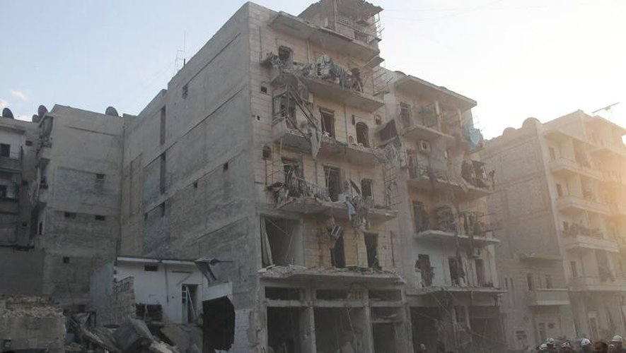 Des habitants devant un immeuble touché par une attaque aérienne de l'armée syrienne, le 29 janvier 2014 à Alep