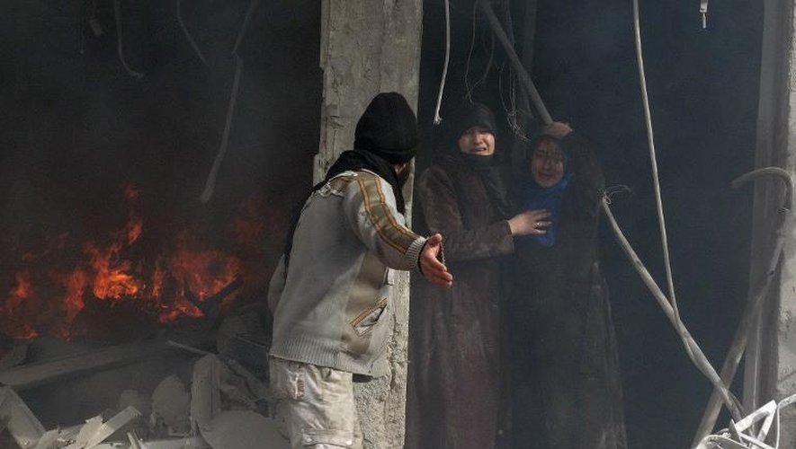 Des habitants dans les décombres d'un immeuble touché par une attaque aérienne de l'armée syrienne, le 30 janvier 2014 à Alep
