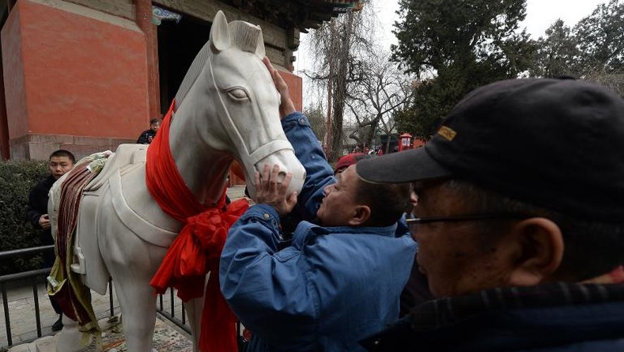 Des visiteurs touchent la statue du Cheval de Jade Blanc au temple Dongyue pour qu'il leur apporte bonheur et prospérité pendant l'année du Cheval, le 31 janvier 2014 à Pékin
