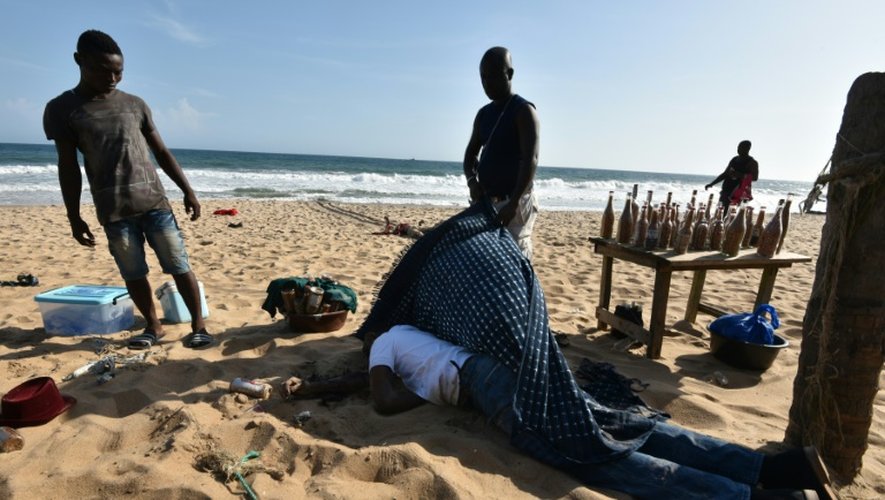 Le corps d'une victime de l'attaque de Grand-Bassam, en Côte d'Ivoire, est recouvert, le 13 mars 2016