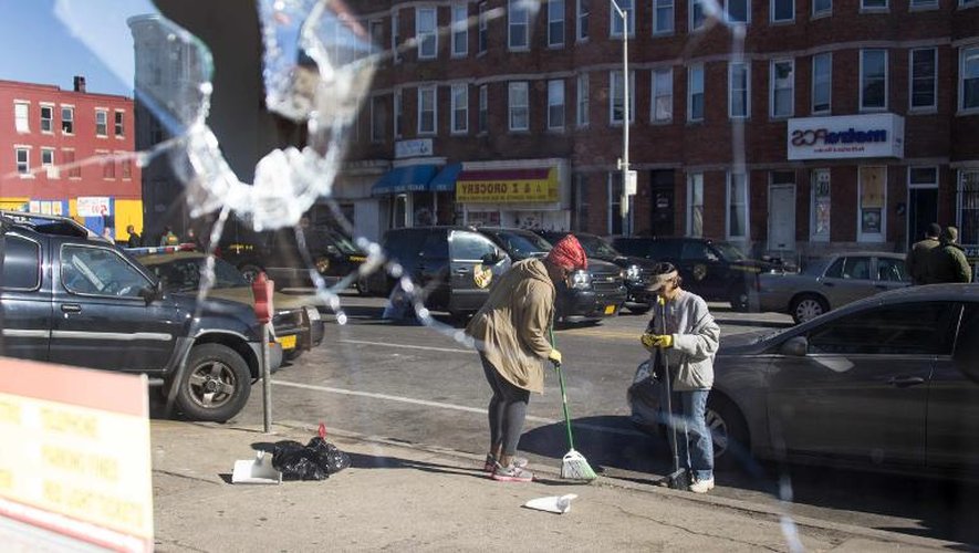 Deux femmes balaient la rue, après une nuit d'émeutes et de casse, à Baltimore, le 28 avril 2015