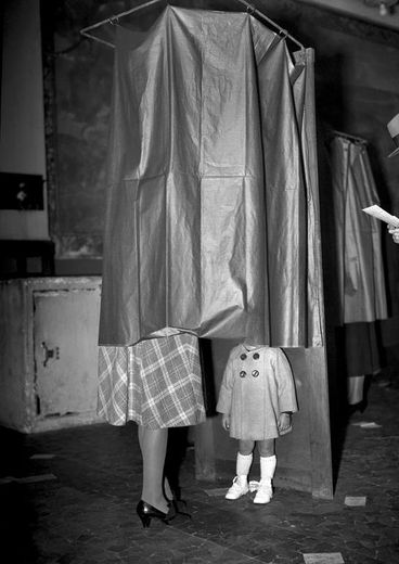 Une femme et sa petite fille dans l'isoloir dans un bureau de vote à Paris lors du référendum du 21 octobre 1945