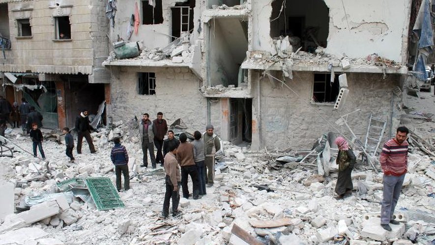Des hommes inspectent les décombres d'un immeuble détruit par des bombardements de l'armée, le 2 février 2014, à Alep