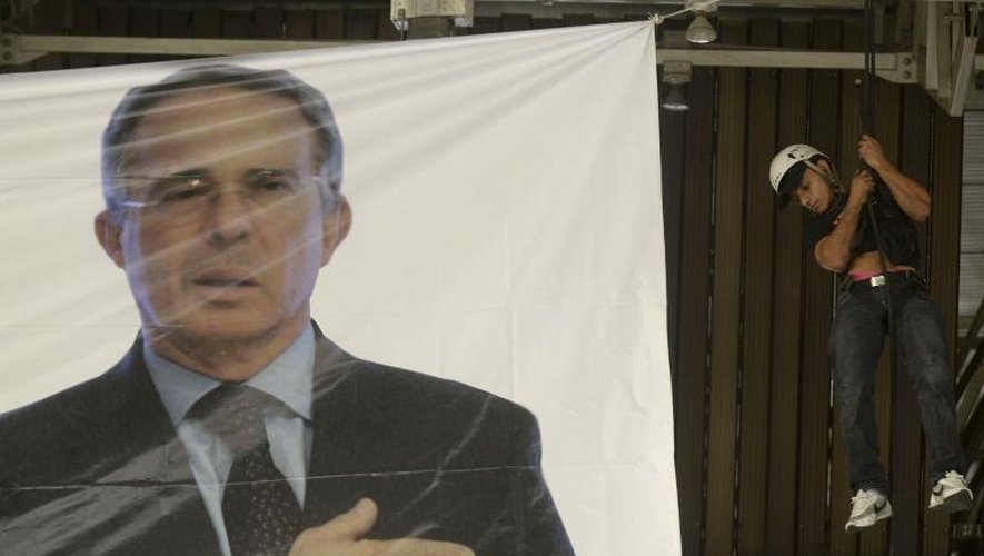 un homme installe une bannière à l'image de l'ancien président colombien Alvaro Uribe, à Medellin le 2 février 2014
