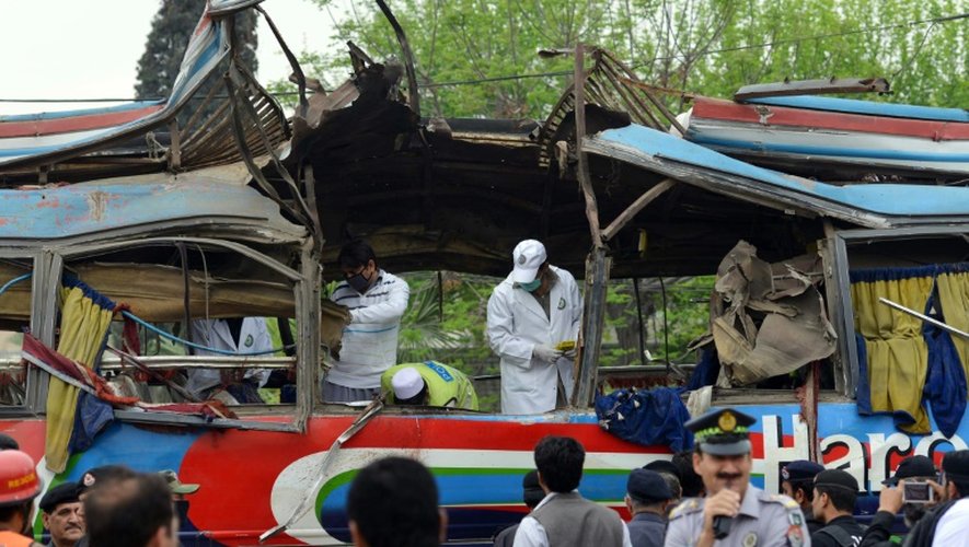 Des volontaires pakistanais et des forces de sécurité inspectent un bus détruit par une bombe qui a fait au moins 16 morts à Peshawar au Pakistan, le 16 mars 2016