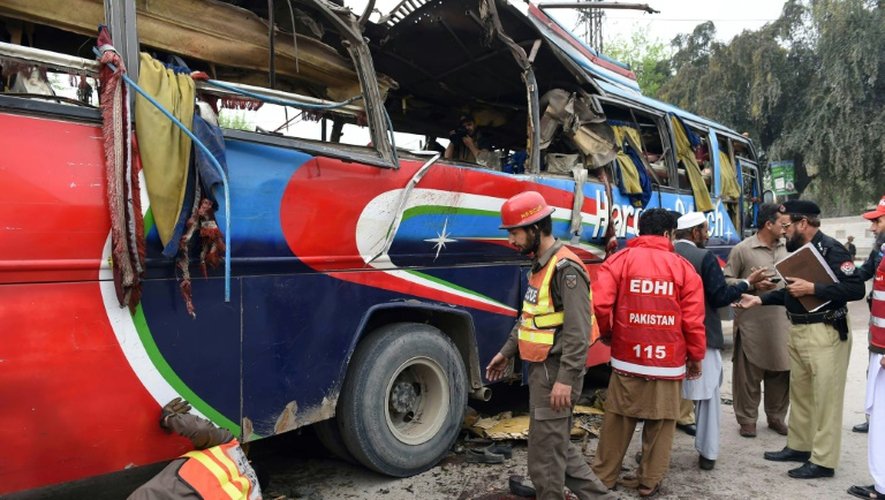 Des volontaires pakistanais et des forces de sécurité inspectent un bus détruit par une bombe qui a fait au moins 16 morts à Peshawar au Pakistan, le 16 mars 2016