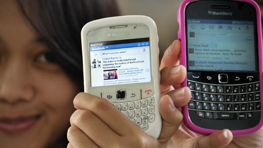 Des jeunes filles montrent leur "mur" Facebook sur leur mobile, à Jakarta le 2 février 2012