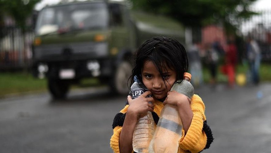 Une jeune népalaise porte des bouteilles d'eau jusqu'à sa tente à Katamandou le 30 avril 2015