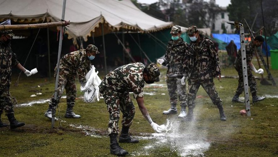 Des soldats népalais dispersent de la chaux en prévention des épidémies autour des tentes des rescapés du tremblement de terre à Katmandou le 30 avril 2015