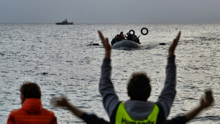 Des militants d'une ONG guident des migrants arrivant à bord d'un bateau arrivant de Turquie à Mytilène sur l'île grecque de Lesbos le 19 février 2016