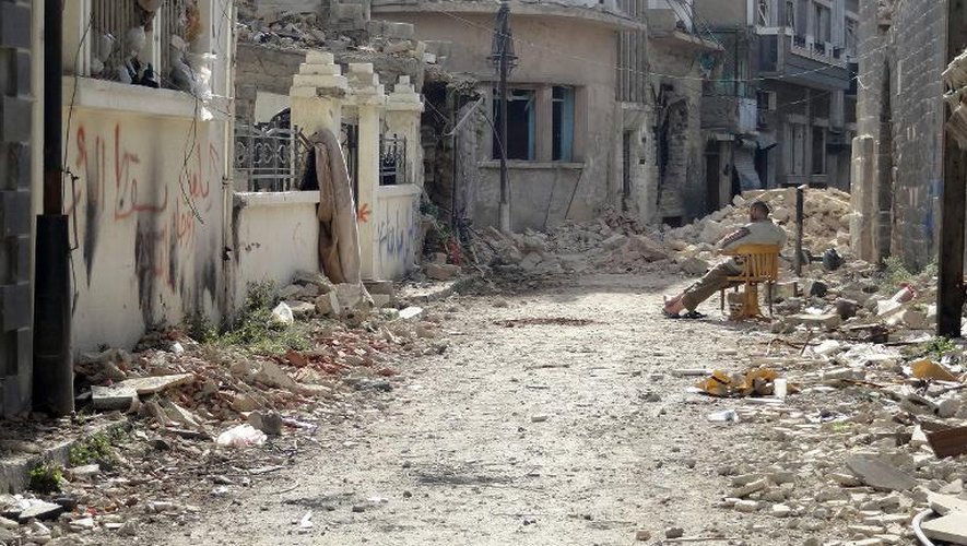 Un homme assis dans une rue détruite de Homs, le 31 janvier 2014 en Syrie