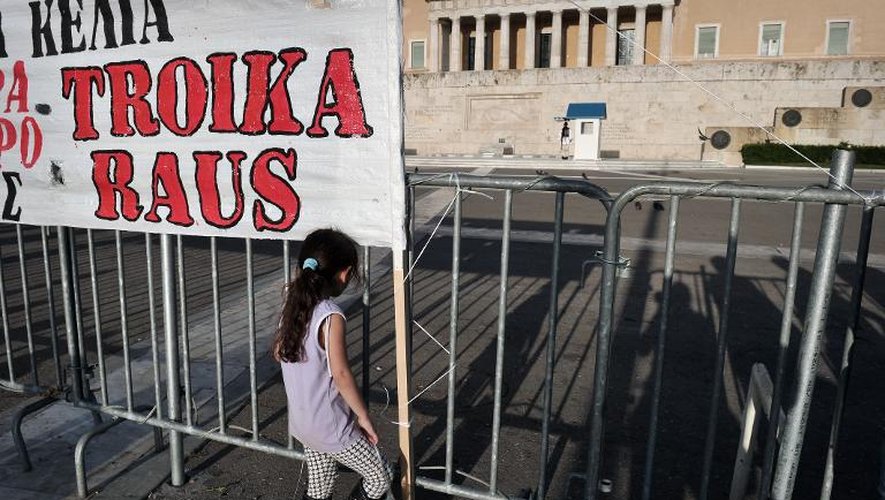 Une petite fille se tient sous la banderole "troika dehors" écrite en allemand et posée devant le Parlement à Athènes, le 28 avril 2013, lors du vote de nouvelles mesures d'austérité budgétaires imposées par la troika pour assurer