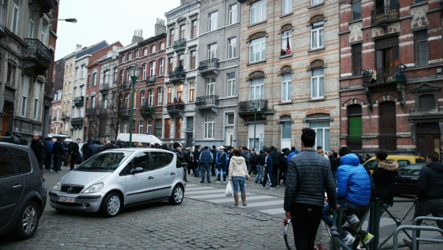 Une foule devant un cordon policier dans la rue des Quatre-Vents à Molenbeek-Saint-Jean (Bruxelles) où un suspect-clé des attentats de Paris a été arrêté après quatre mois de cavale, le 18 mars 2016