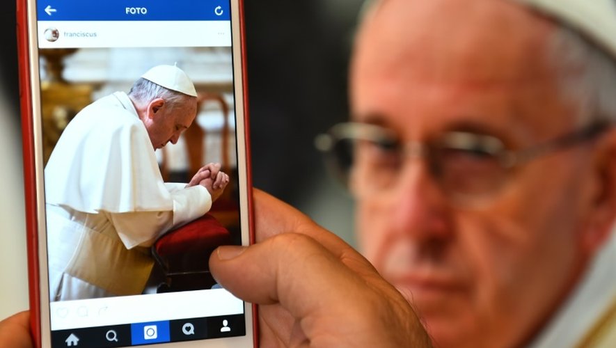 Un homme regarde le compte Instagram du pape sur son écran de portable, le 19 mars 2016 à Rome