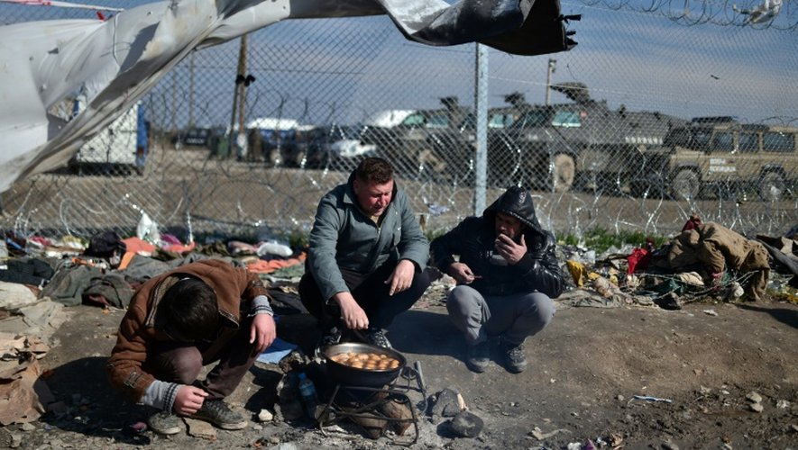 Des migrants font cuire des pommes de terre dans un camp de réfugiés à la frontière entre la Grèce et la Macédoine à Idomeni, le 19 mars 2016