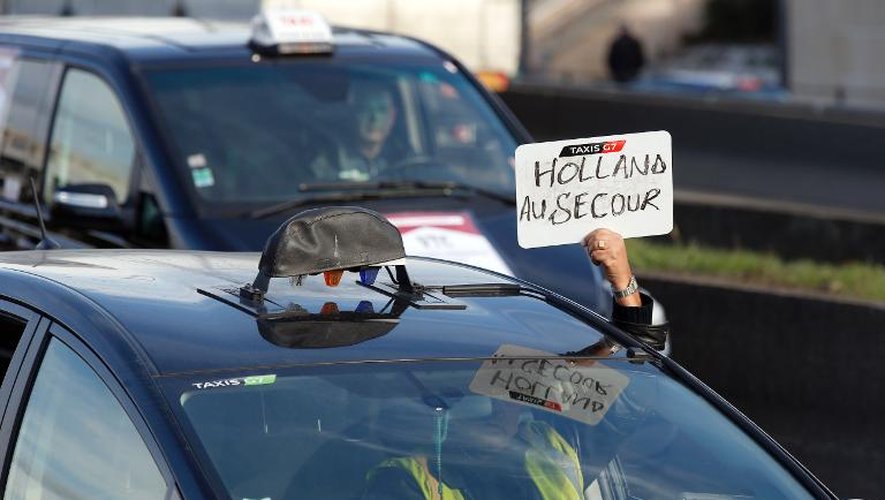 Un chauffeur de taxi brandit une pancarte appelant François Hollande à l'aide, sur le périphérique parisien le 10 février 2014