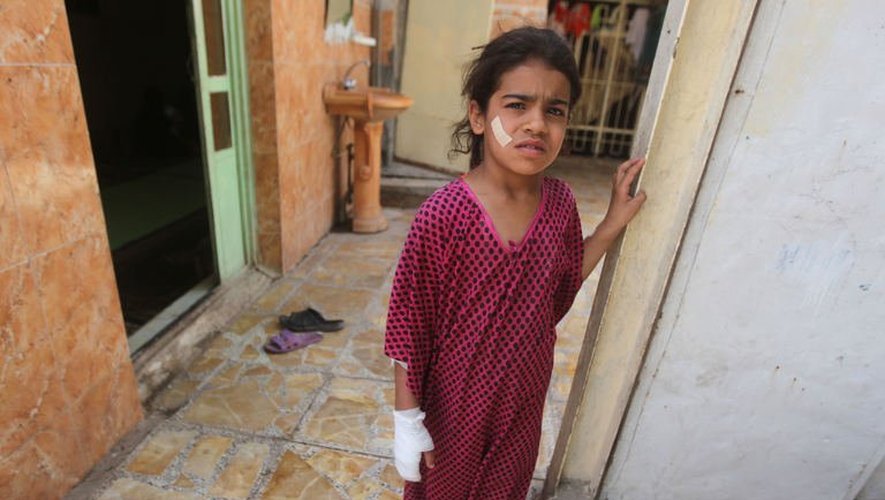 Une enfant, blessée, à l'entrée de sa maison à Bagdad, le 16 mai 2013, après un attentat à la voiture piégée