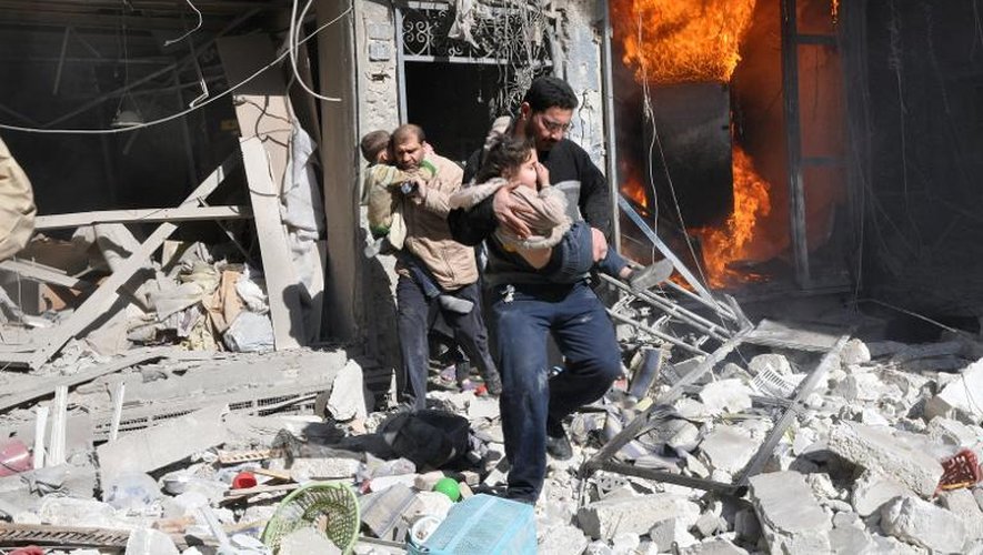 Des hommes portant des enfants dans leurs bras, sortent d'un bâtiment détruit par une bombe, lors d'une attaque aérienne du régime syrien, le 8 février 2014 à Alep