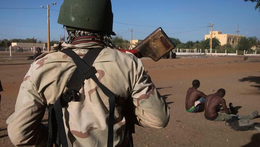 Un soldat malien surveillent deux hommes suspectés d'être membres du Mujao, le 22 février 2013 à Gao, dans le nord du Mali