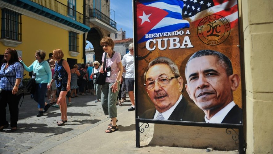 Des touristes se promènent près d'une affiche du président cubain Raul Castro et de son homologue américain Barack Obama à La Havane, le 18 mars 2016