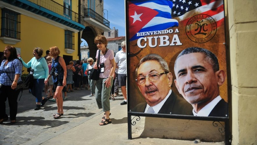 Des touristes se promènent près d'une affiche du président cubain Raul Castro et de son homologue américain Barack Obama à La Havane, le 18 mars 2016