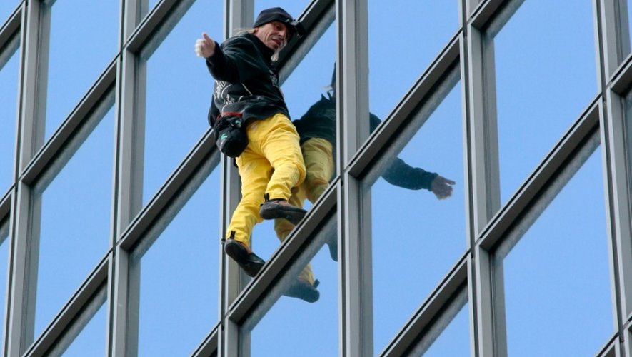 Le "Spiderman français", Alain Robert, escalade à mains nues la tour Total du quartier d'affaires de la Défense, le 21 mars 2016