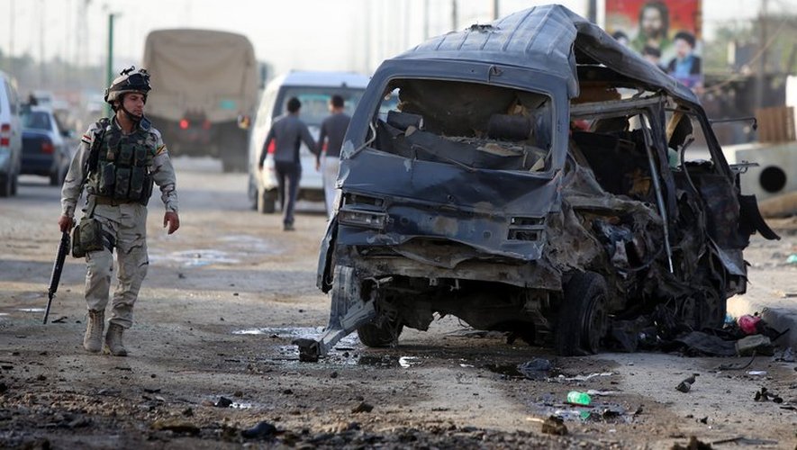 Un soldat irakien près d'un véhicule détruit après un attentat à Bagdad, le 16 mai 2013