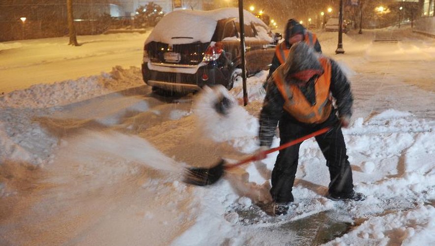 Des employés municipaux dégagent les trottoirs à Chevy Chase pendant une violente tempête de neige, le 13 février 2014 dans le Maryland