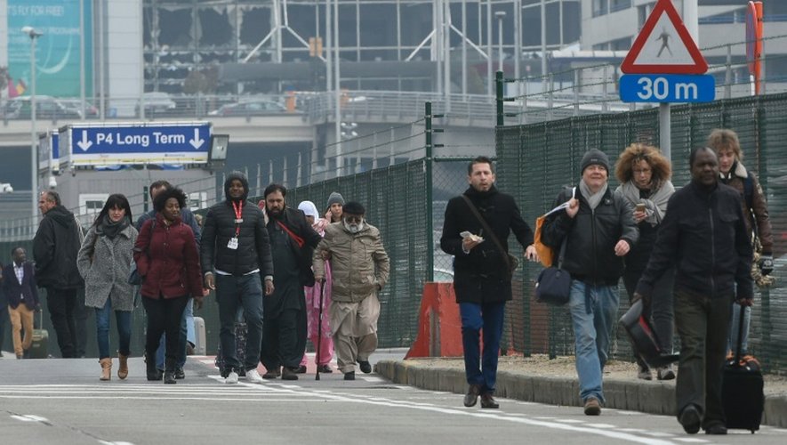 Des passagers évacuent l'aéroport de Bruxelles, le 22 mars 2016 après deux explosions