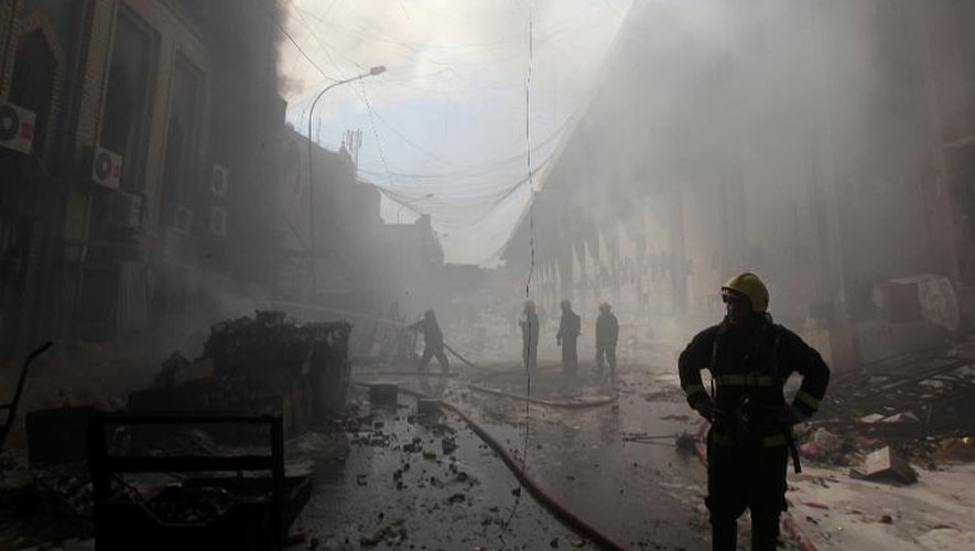 Des pompiers éteignent un feu dans un marché de Bagdad où un attentat a eu lieu le 13 février 2014