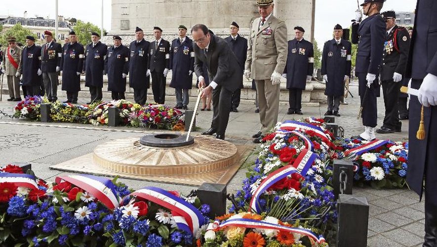 Le président français François Hollande ravive la flamme de la tombe du soldat inconnu sous l'Arc de Triomphe à Paris le 8 mai 2015