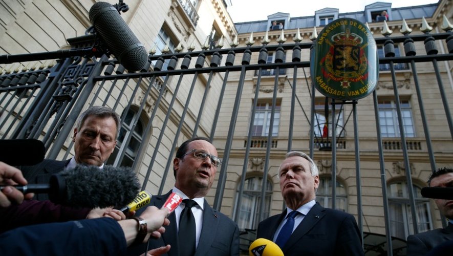 Francois Hollande fait une déclaration près de l'ambassadeur de Belgique en France Vincent Mertens et le ministre français des Affaires étrangères Jean-Marc Ayrault devant l'ambassade à Paris le 22 mars 2016