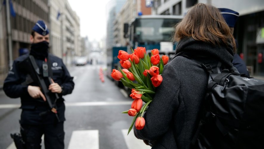 Une femme arrive avec des fleurs à la station de métro de Maelbeek le 23 mars 2016 à Bruxelles